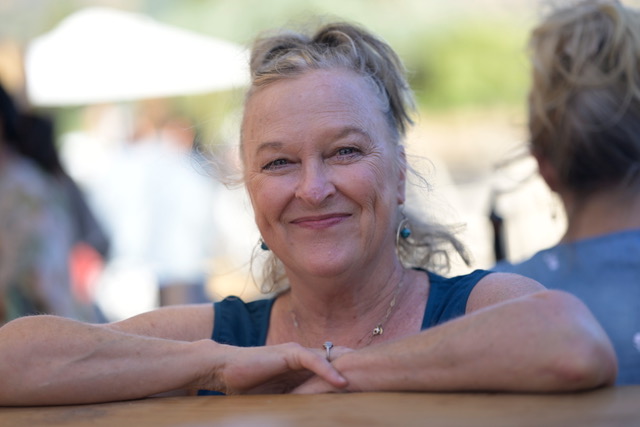 Pam Bell smiling warmly with her arms resting on a table.